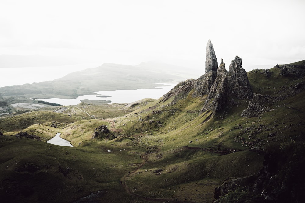 a rocky mountain with a body of water in the distance with The Storr in the background