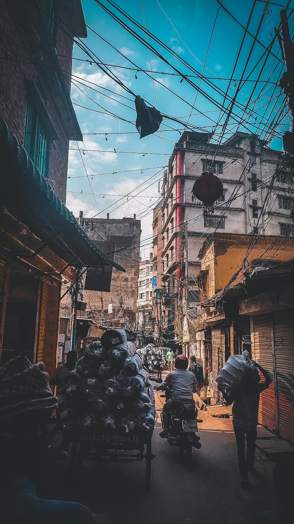 a group of people riding motorcycles down a narrow street