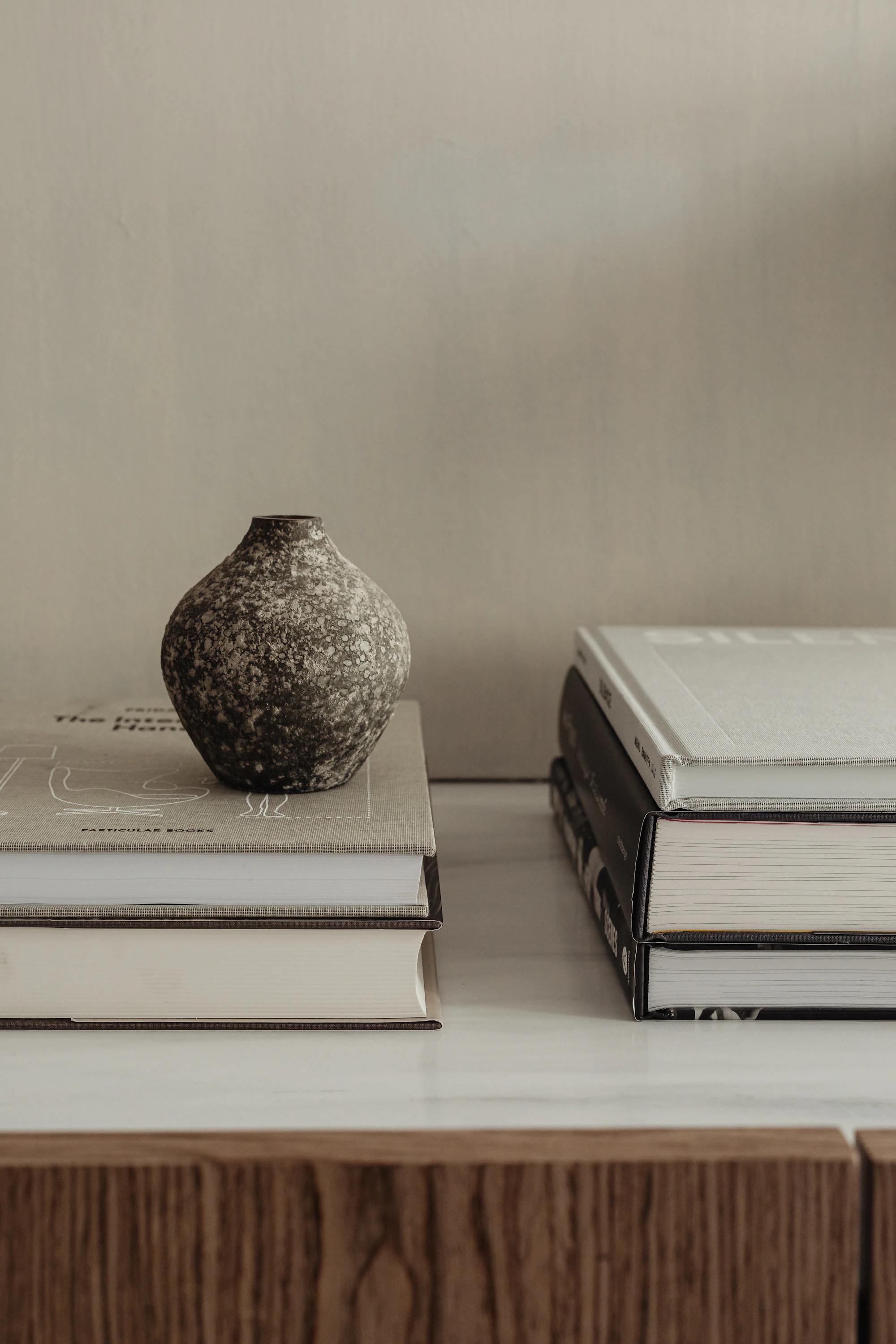 Nature morte éditoriale — vase en céramique texturée posé sur une pile de livres