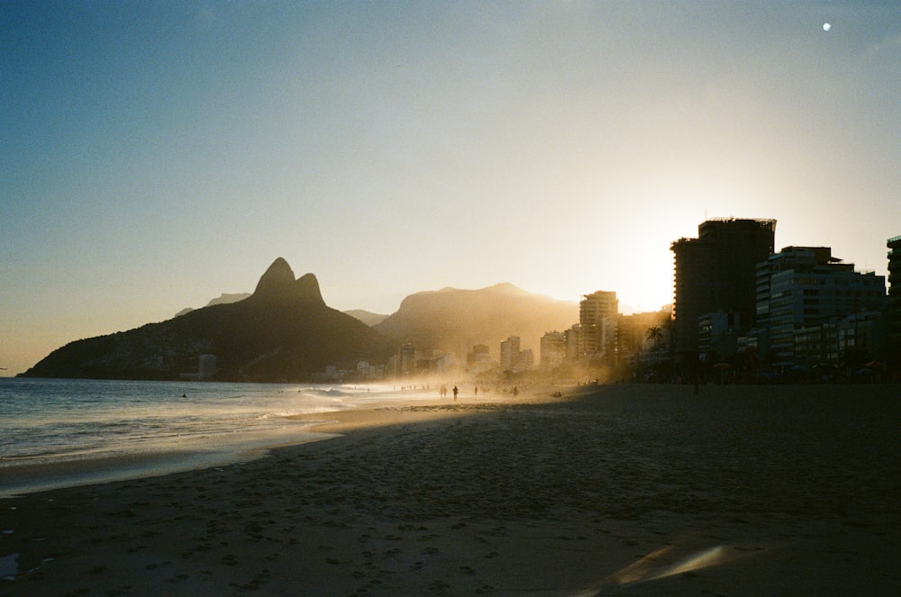 a beach with buildings and a hill in the background