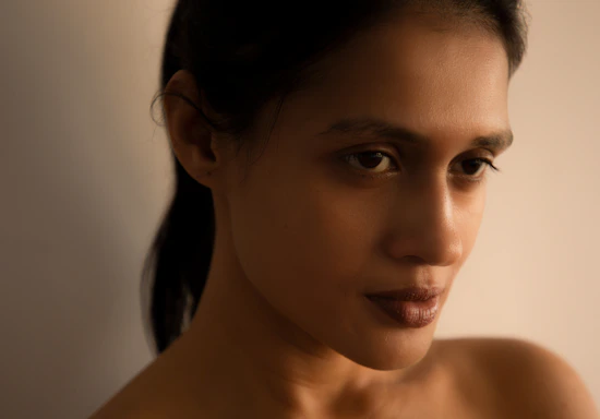 A warm, minimalist portrait photography setup with soft natural light highlighting the subject's face.