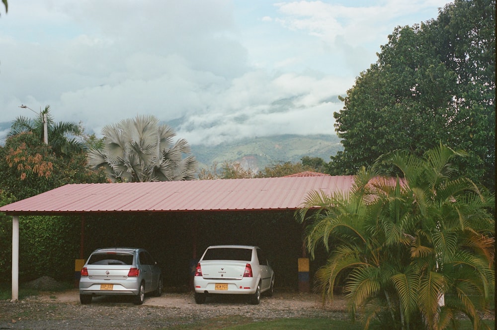 a couple of cars parked outside a building with trees and mountains in the background