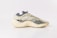 A modern sneaker with a sleek, futuristic design featuring a translucent upper and contoured sole. The shoe combines various textures and patterns, incorporating shades of beige, gray, and black for a sophisticated look.