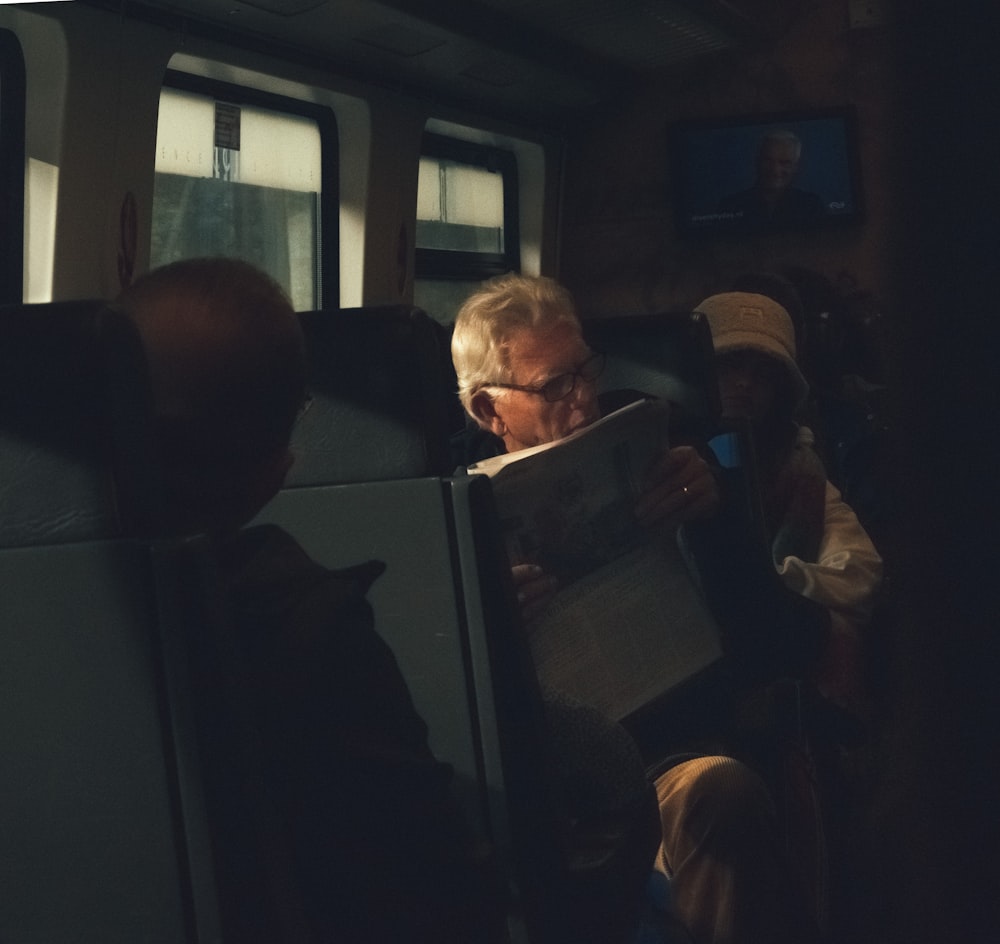 a group of people sitting in a bus looking at a laptop
