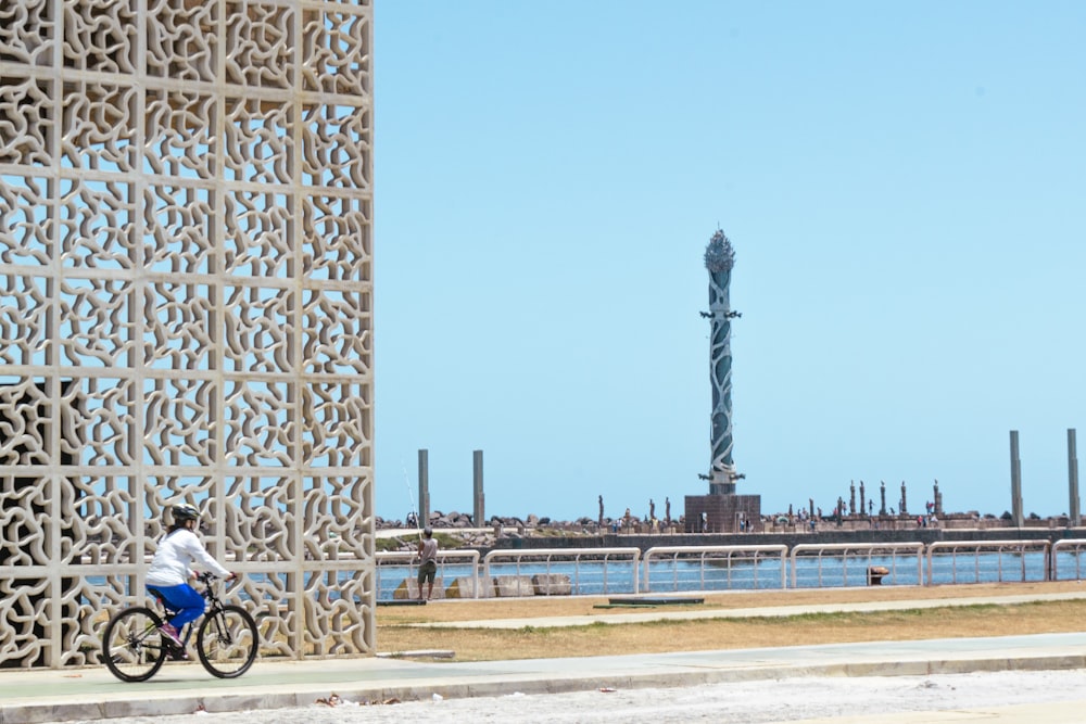 a person riding a bicycle on a road next to a large metal structure