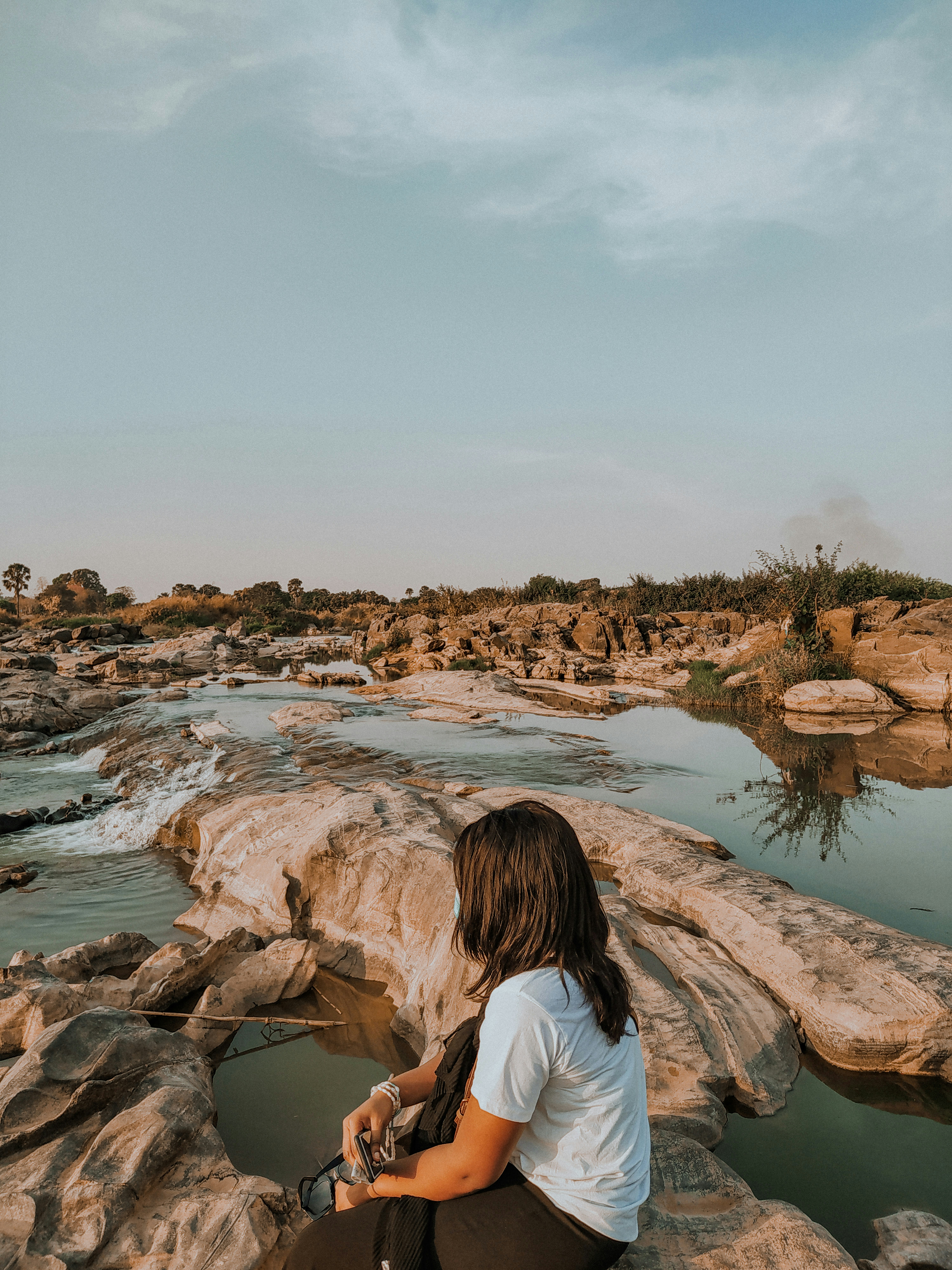 a person sitting on a rock looking at a river
