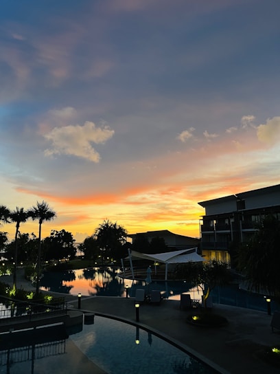 A serene view of the luxury villa's pool area at sunset, with colorful underwater LED lights glowing softly.