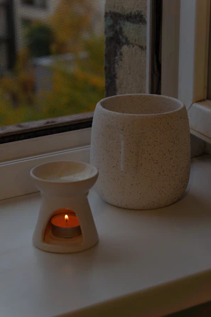 A candle melting gently in a handmade ceramic holder with natural light streaming in.