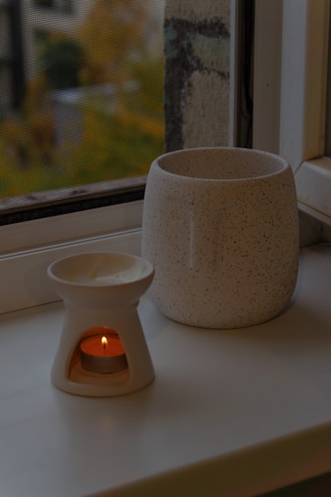 A cozy wooden tea light holder glowing softly on a rustic windowsill.