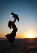 a man carrying a baby on his back on a beach