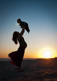 a man carrying a baby on his back on a beach