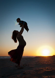 a man carrying a baby on his back on a beach