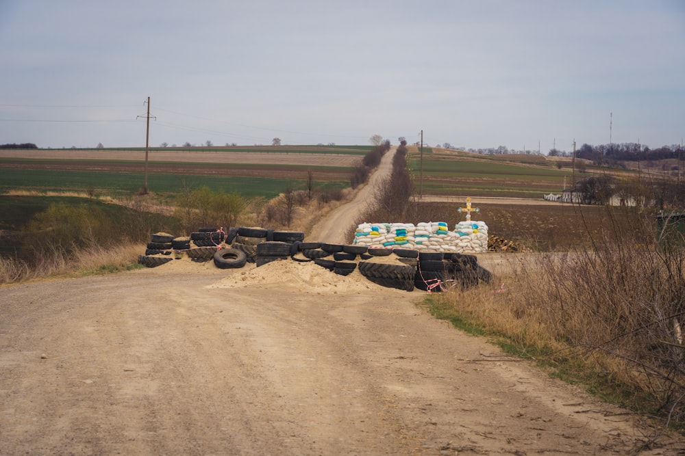 a dirt road with a pile of tires on the side