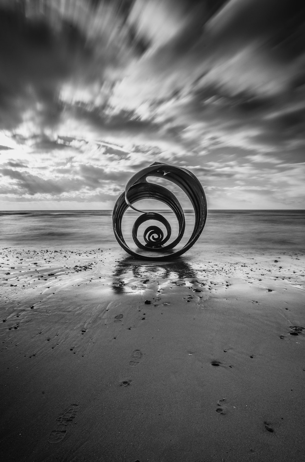 a black and white photo of a wheel on a beach