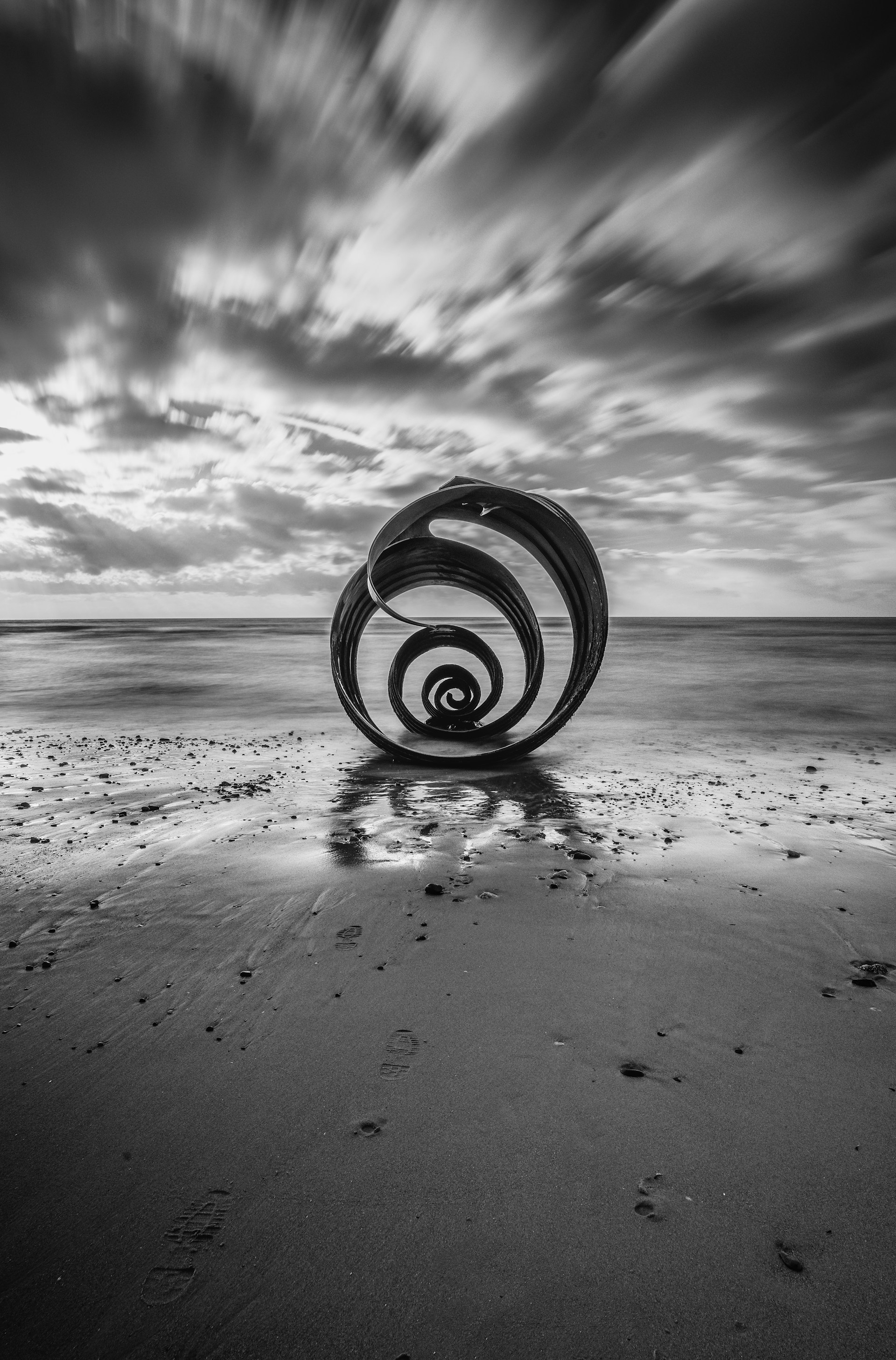 a black and white photo of a wheel on a beach