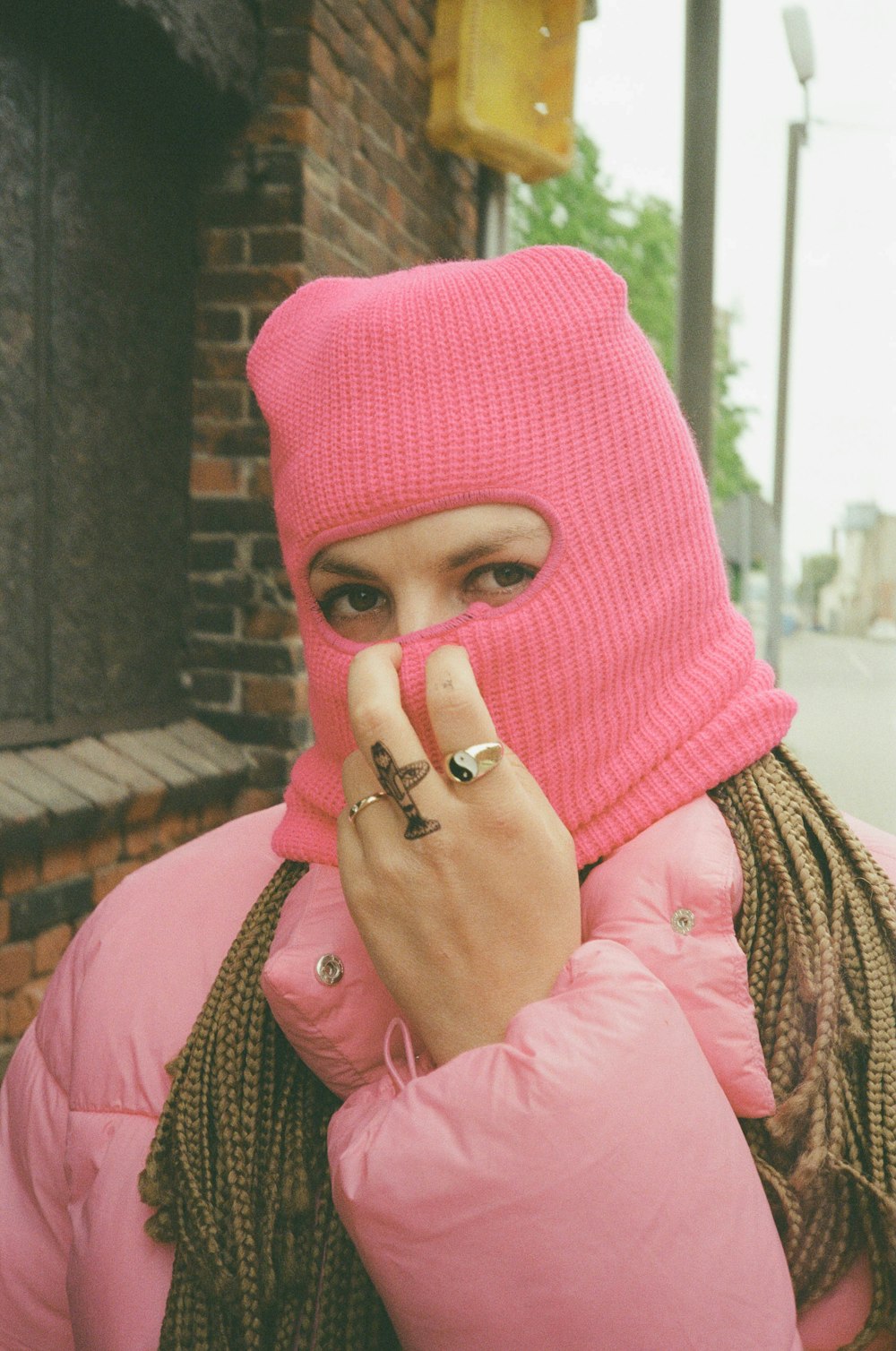 a person wearing a pink head scarf and holding a finger up