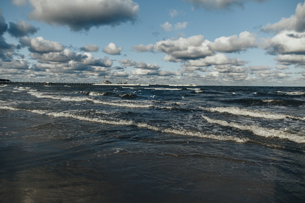 a beach with waves and clouds