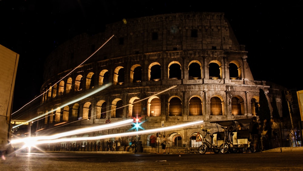 a large stone building with arches with Colosseum in the background