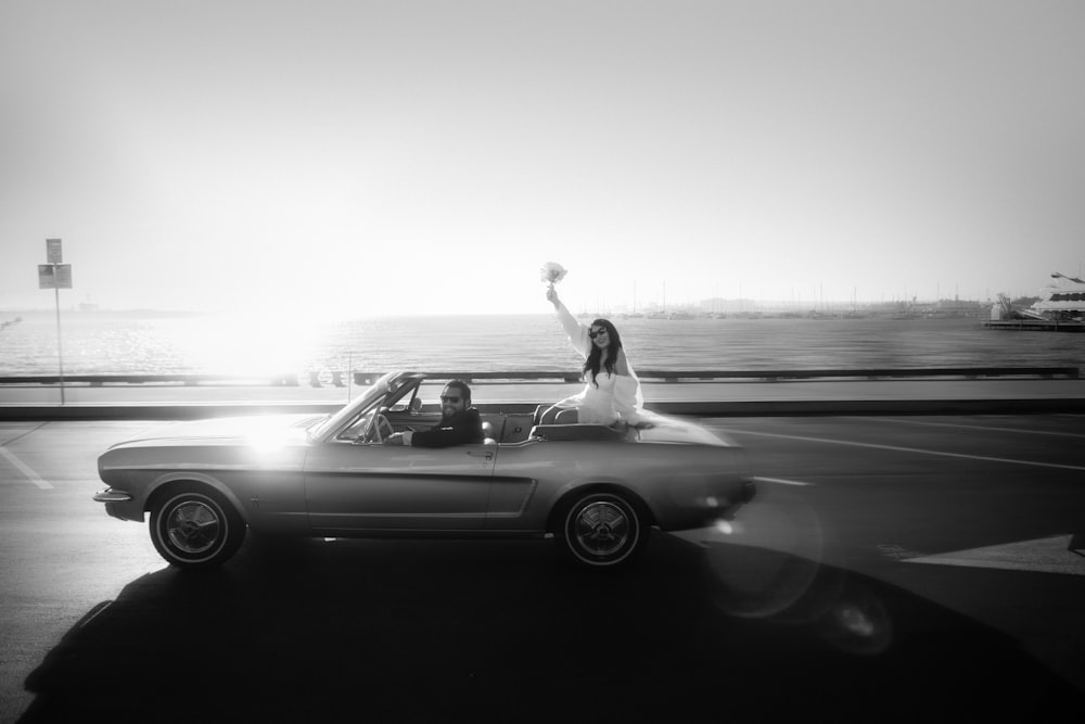 a bride and groom in a convertible car