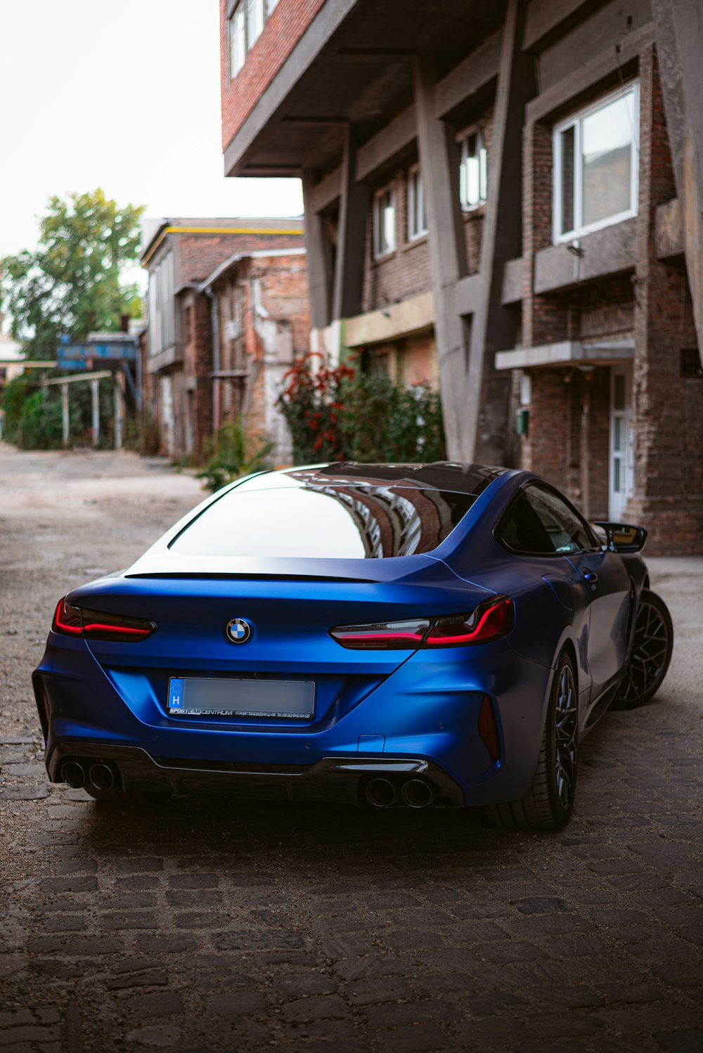 a blue sports car parked in front of a brick building