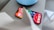 A smartphone displaying various app icons on its screen, placed on a light-colored surface near a blue circular object. Part of a white object is partially visible in the foreground.