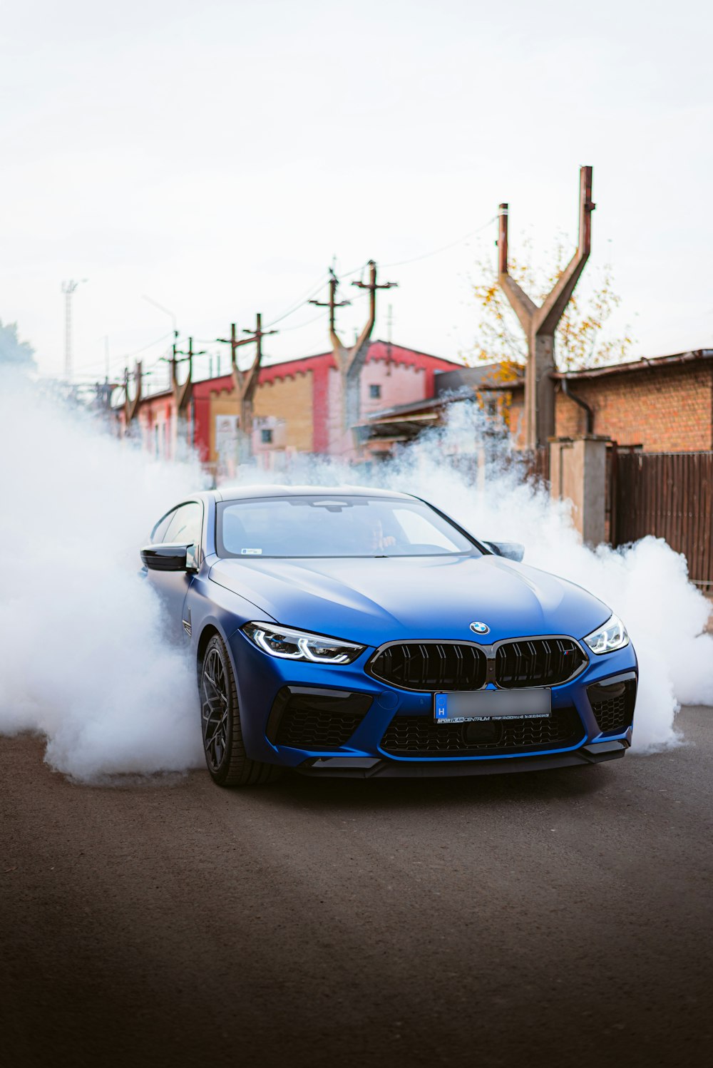 a blue car on a road with smoke coming out of it