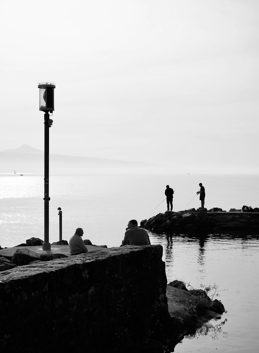 a group of people fishing on a rocky shore