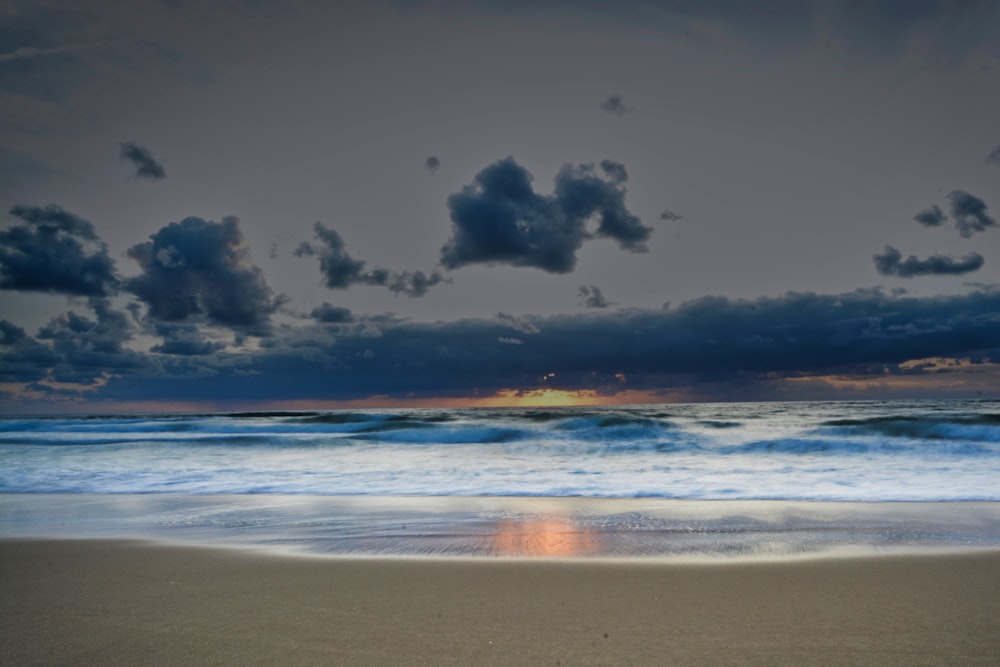 a beach with waves and clouds