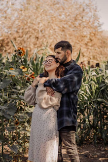 A candid photo of Wall and Mariana laughing together in a sunlit garden with soft pink flowers around.