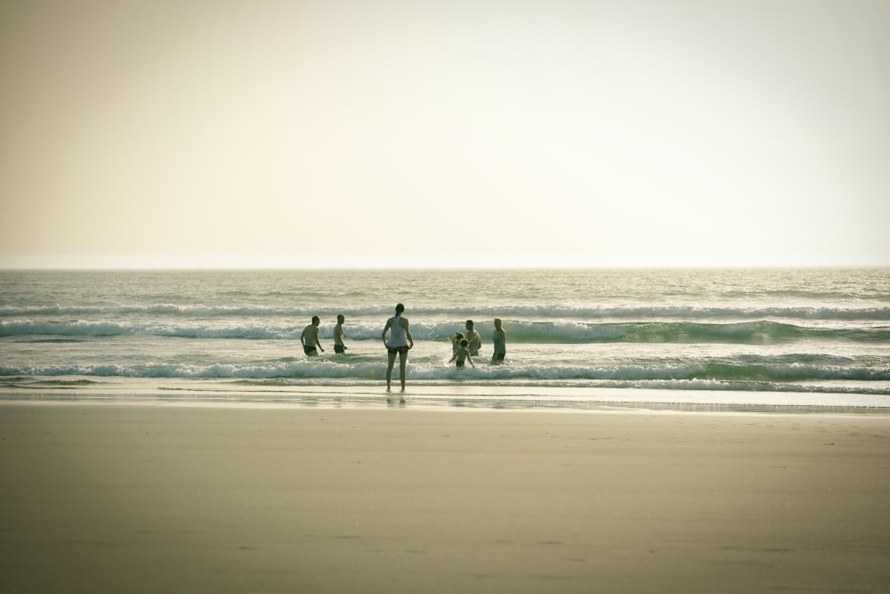 a group of surfers walk across the beach