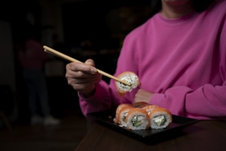 a person holding a wooden spoon over a tray of food