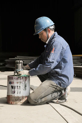 a man wearing a hard hat and holding a metal container