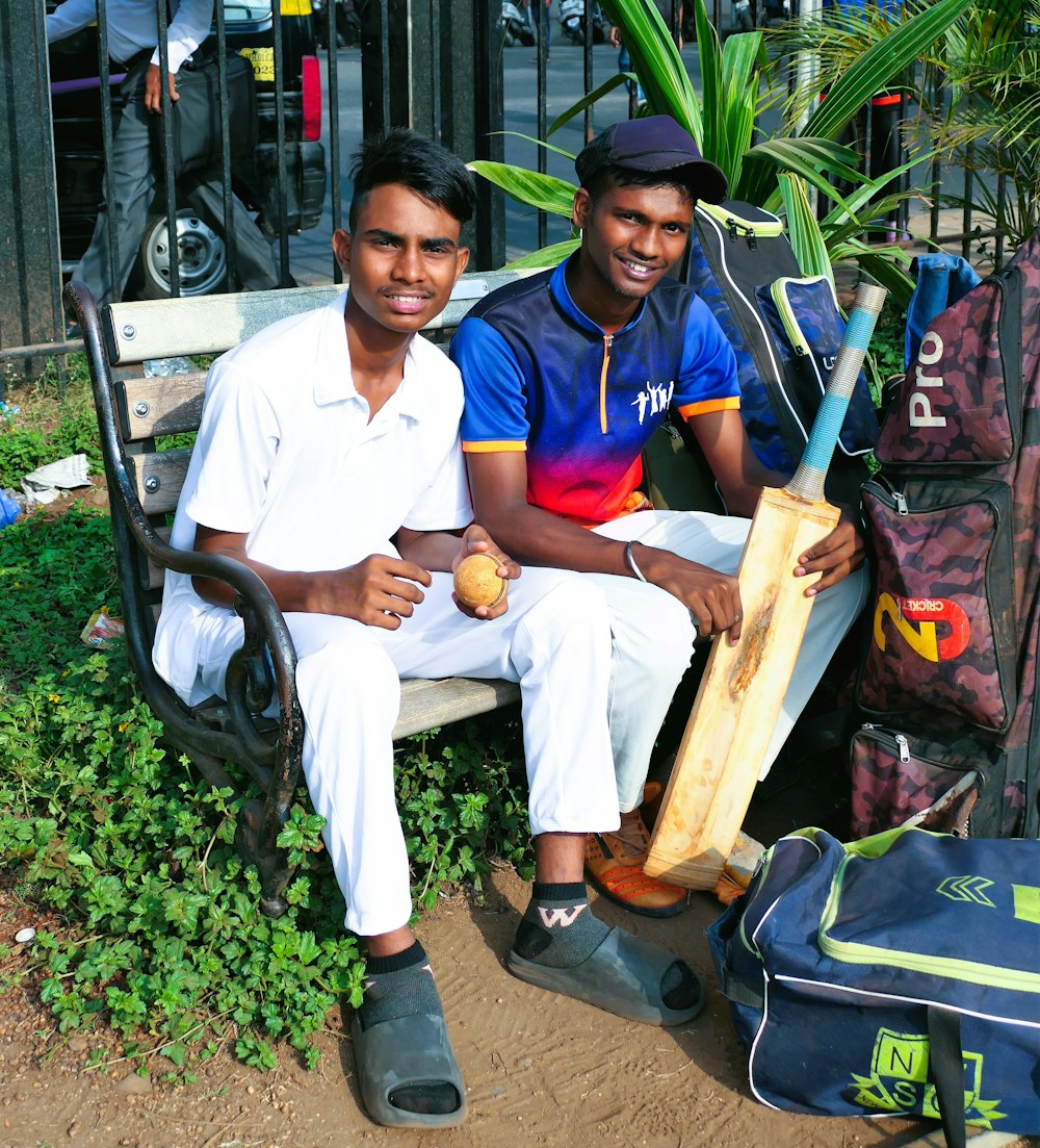 a couple of men sitting on a bench with a bag and a bag