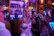A lively group of friends singing karaoke with colorful lights in a cozy bar setting.