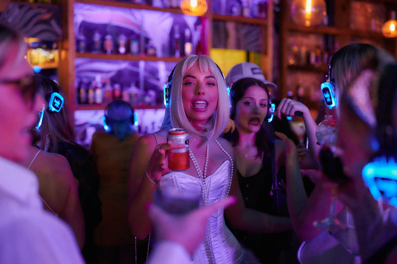 A lively group of friends singing passionately in a cozy, modern karaoke studio with colorful LED lights.