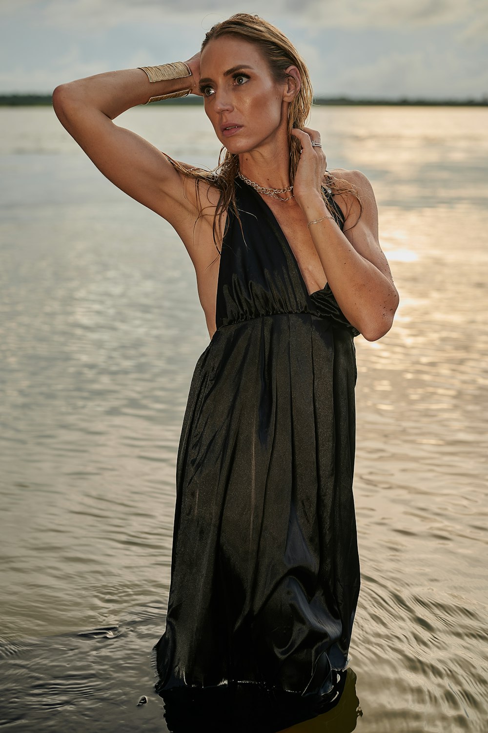 a woman in a black dress standing in front of a body of water