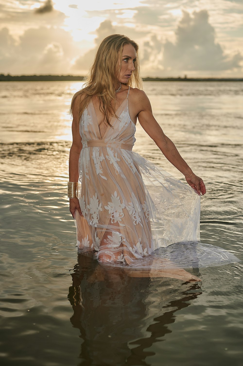une personne en robe blanche debout dans l’eau