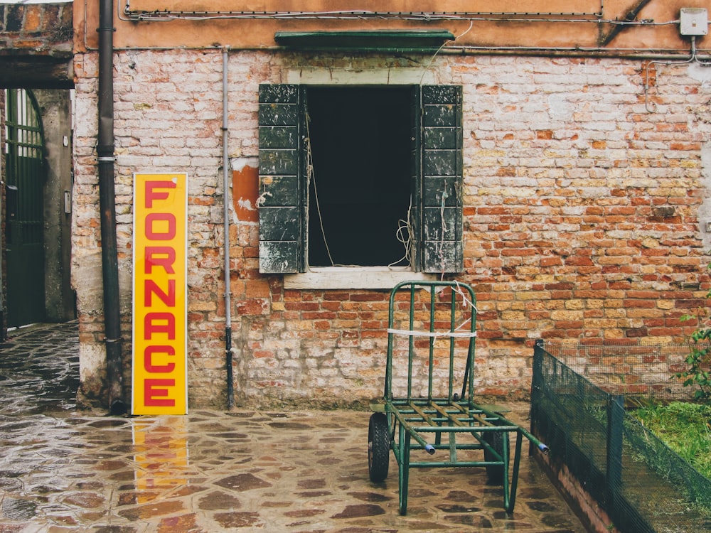 a green cart parked in front of a brick building