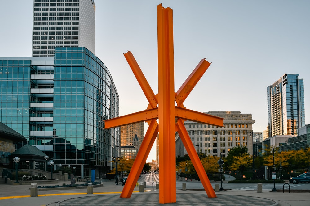 a large orange sculpture in a city