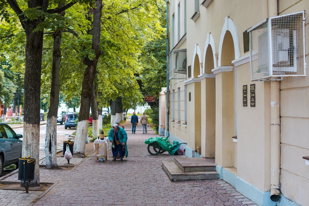 a group of people walking down a sidewalk next to a building