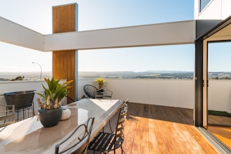 a table with chairs and plants on it by a window