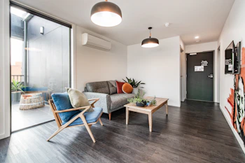 A bright living room with timber floors, grey seating and clean white walls