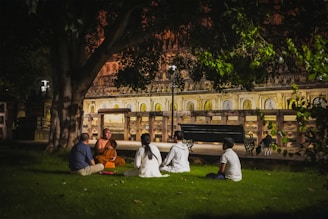 a group of people sitting on the grass in front of a building