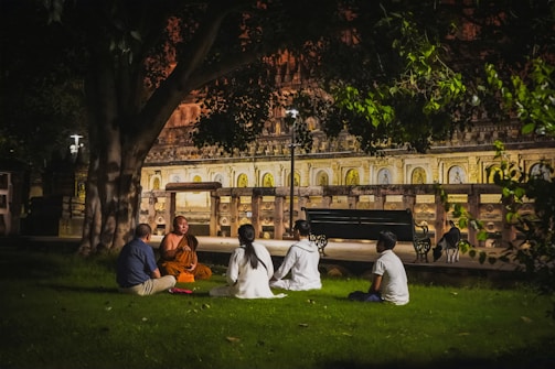 a group of people sitting on the grass in front of a building