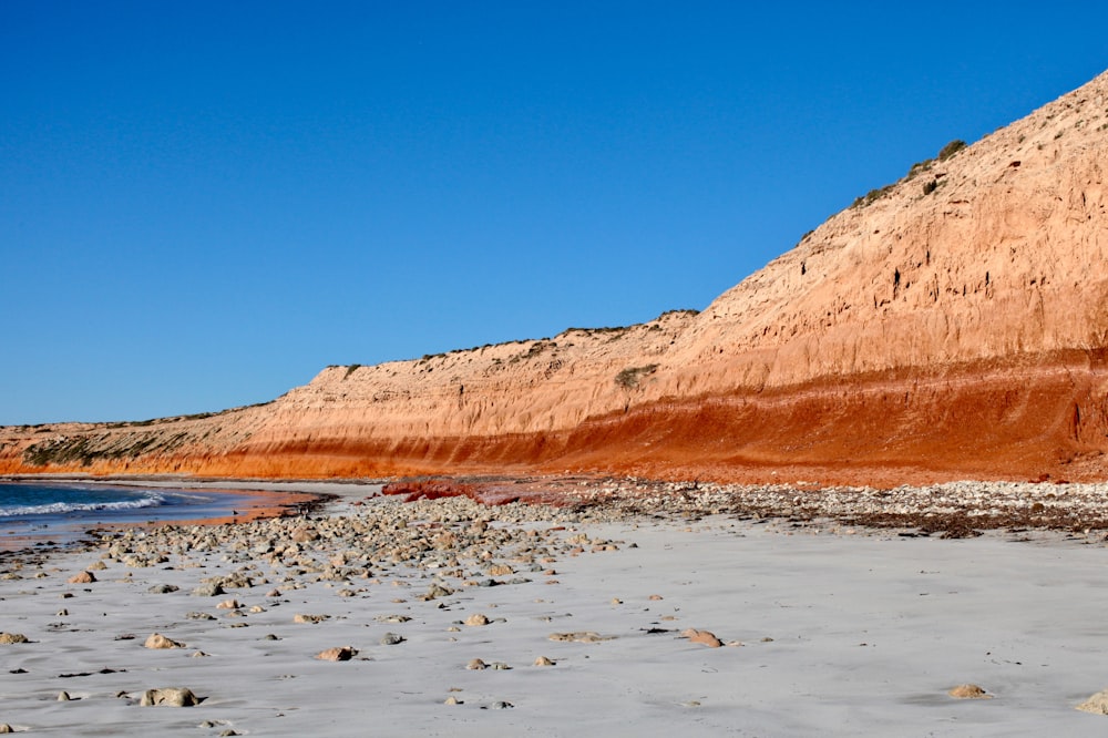 a sandy beach with a hill in the background