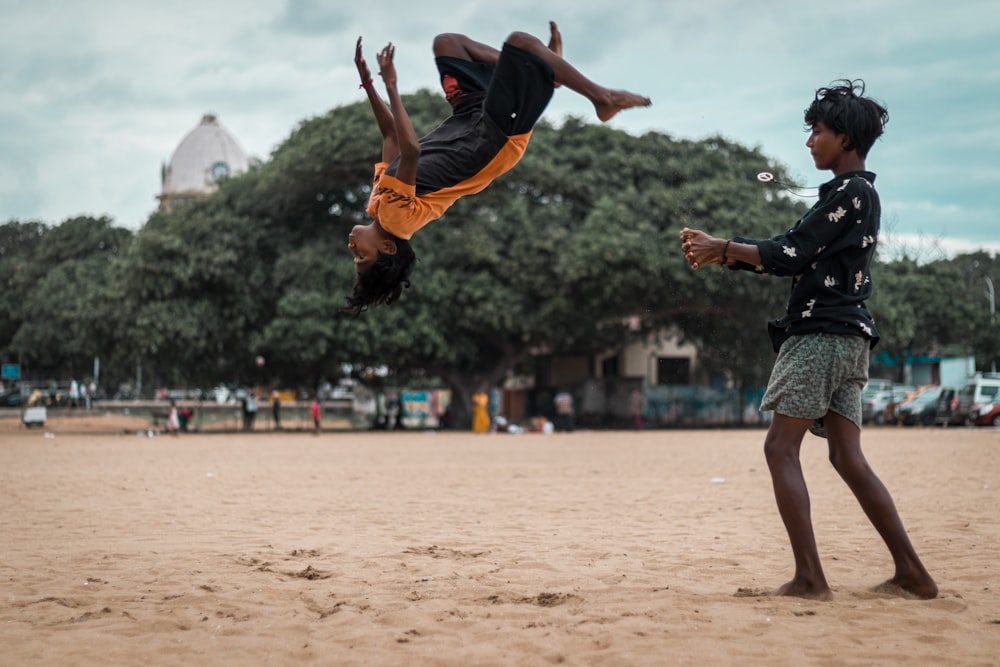 a man holding a boy on his back on a beach