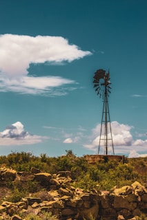 A rustic windmill standing tall against a bright blue sky at Sierra Windmill Mini Farm