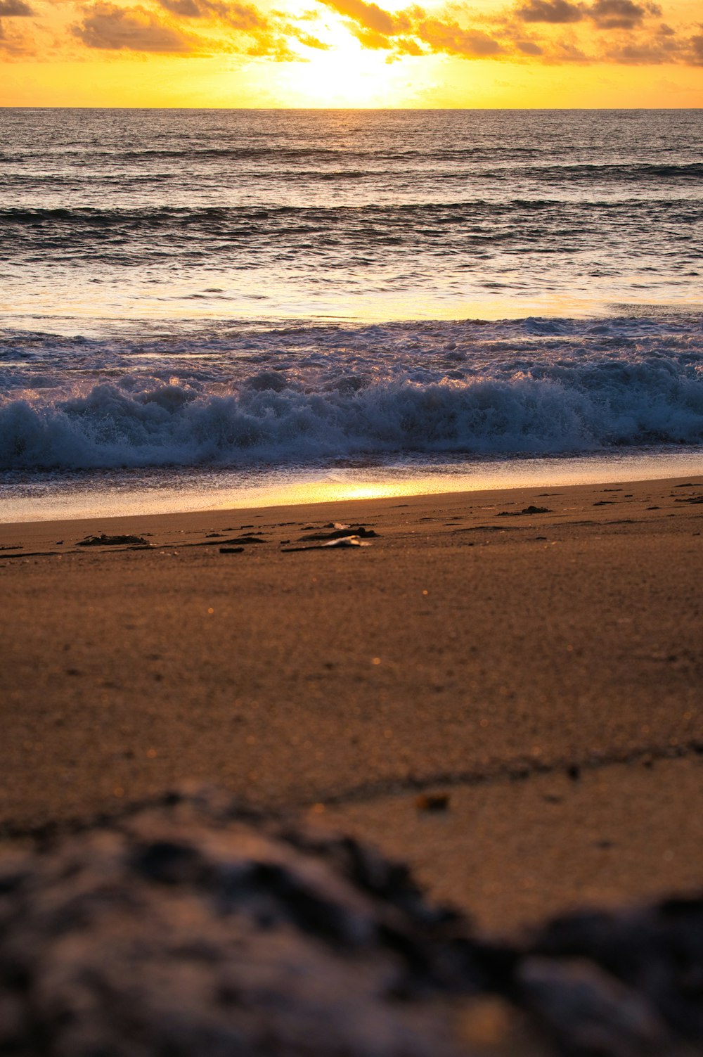 une plage avec des vagues et un coucher de soleil
