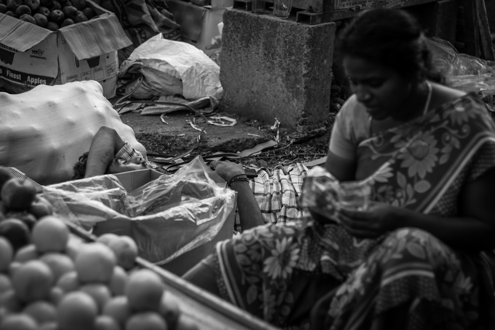 a person sitting next to a pile of produce