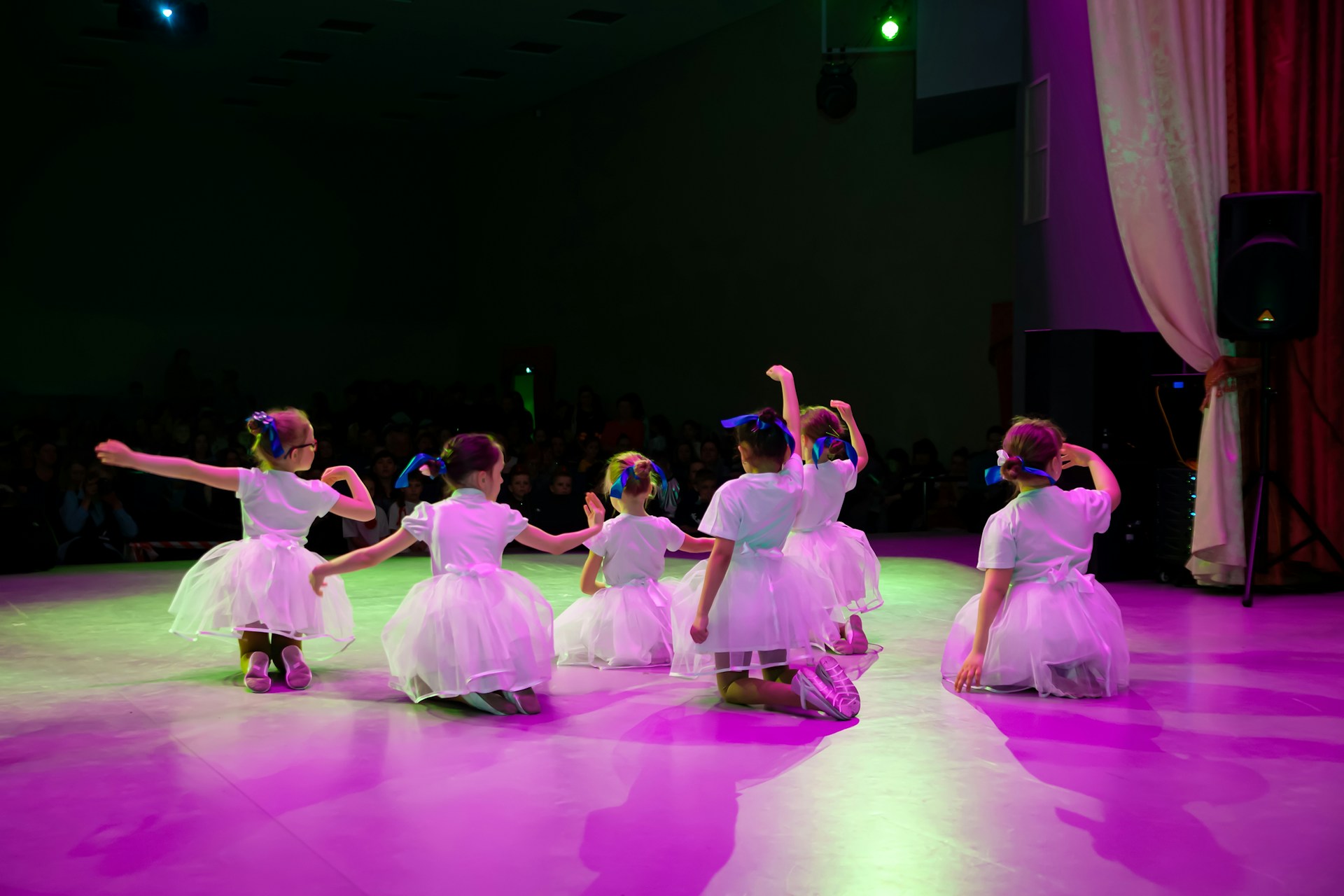 a group of children in white dresses dancing on a stage